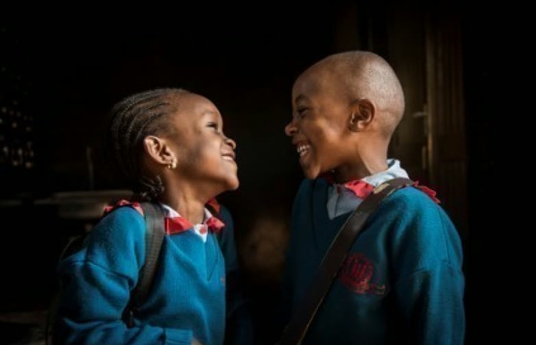 Deux enfants en uniforme scolaire se sourient
