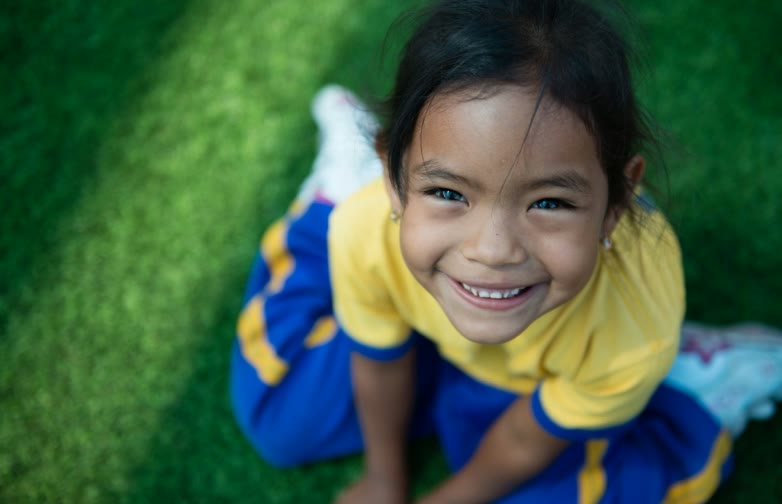 Une petite fille allongée dans l'herbe sourit