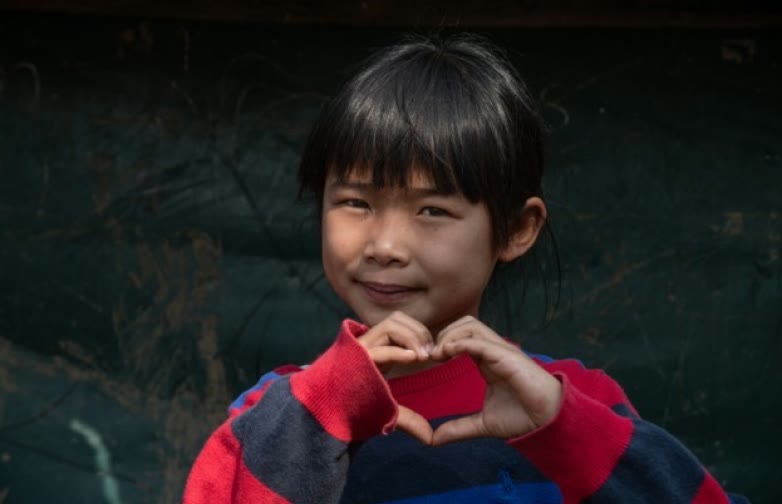 Un enfant forme un cœur avec ses mains