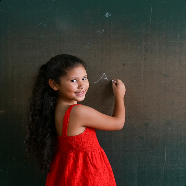 Une petite fille écrit au tableau dans sa salle de classe
